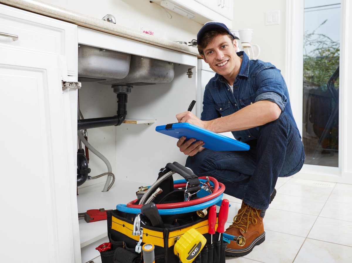 Licensed plumber inspecting under-sink plumbing during a free plumbing inspection